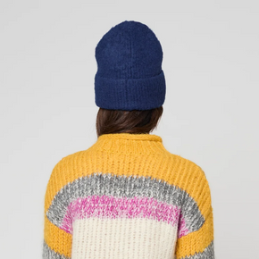 Person wearing a colorful sweater and blue beanie with a white background