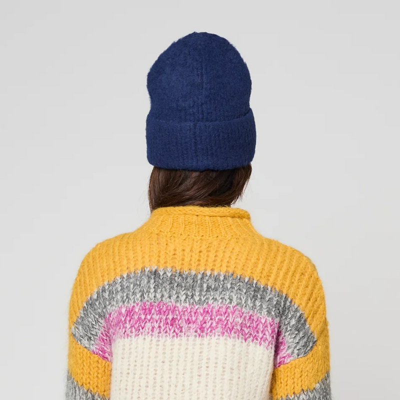 Person wearing a colorful sweater and blue beanie with a white background