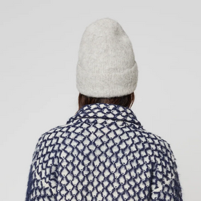 Person wearing a patterned coat and grey knit hat on a plain background