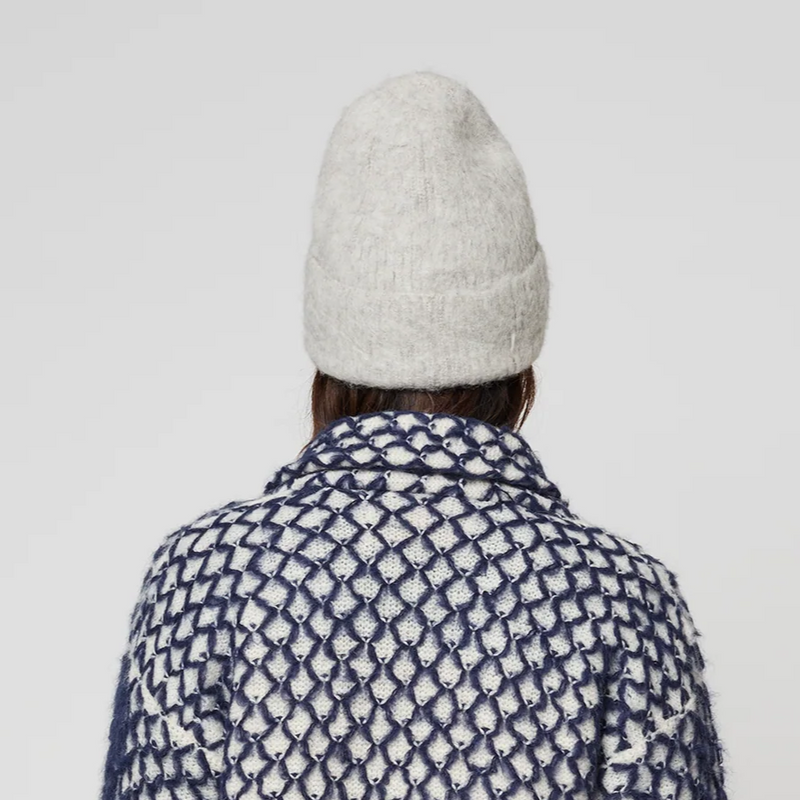 Person wearing a patterned coat and grey knit hat on a plain background