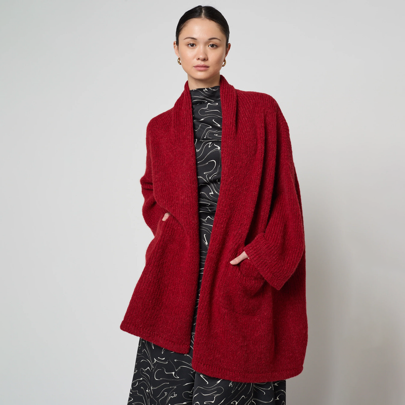 Person wearing a red coat against a plain background