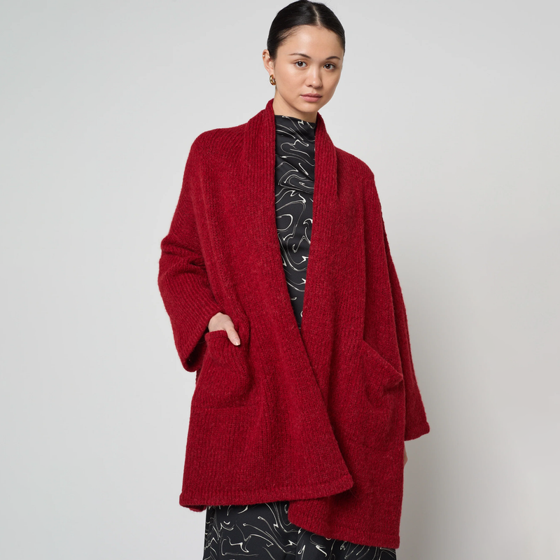 Person wearing a red cardigan against a plain background
