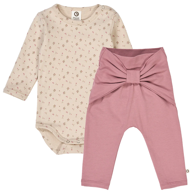 Beige baby bodysuit with floral pattern and pink pants with bow feature on a white background