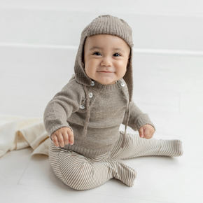 Baby wearing a knitted brown outfit with a hood on a white background