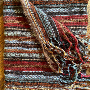 Scarf with multicolored stripes and fringes on a wooden surface