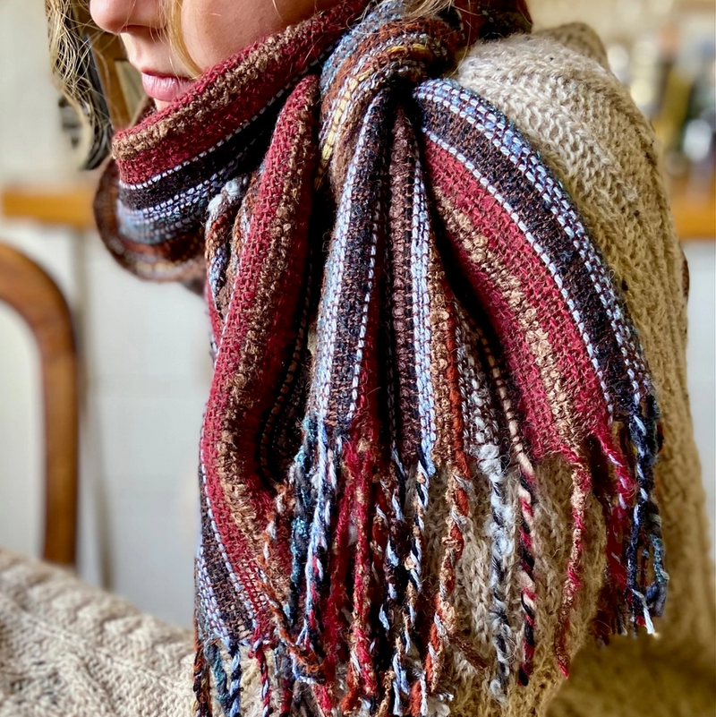 Person wearing a colorful knitted scarf with a blurred background