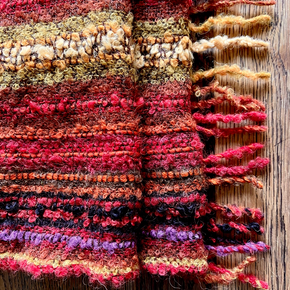 Close-up of a textured scarf with multicolor yarn on a wooden surface