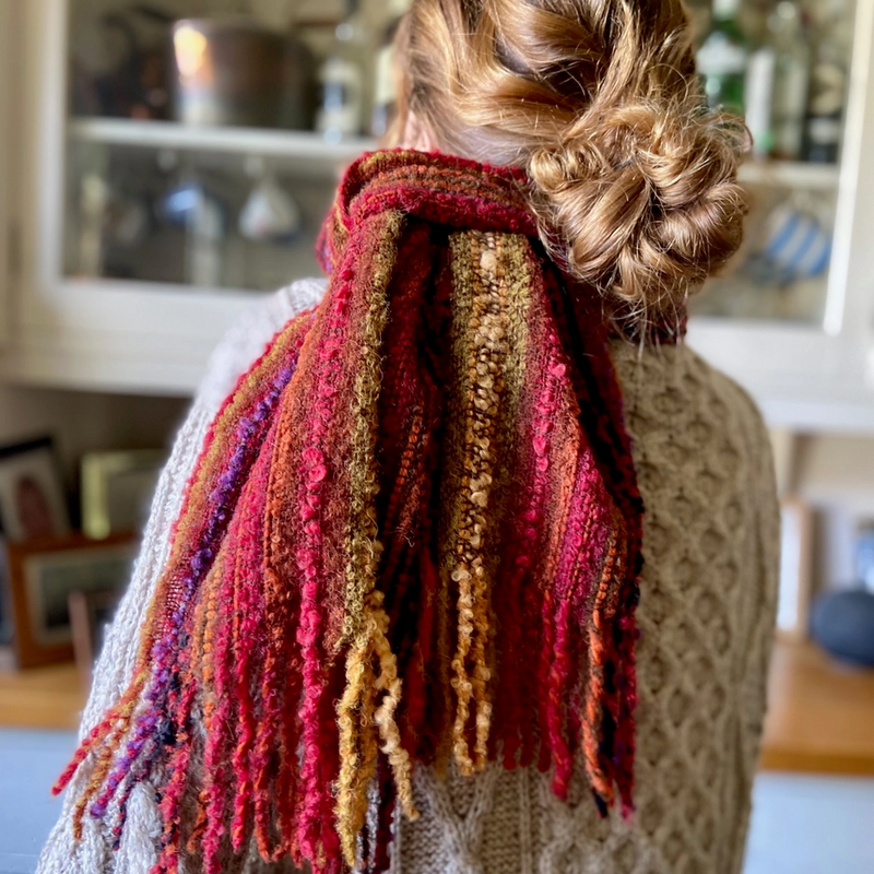 Person wearing a colorful scarf with a blurred indoor background