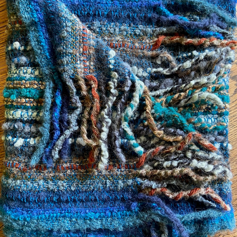 Scarf with blue and multicolored yarn on a wooden surface