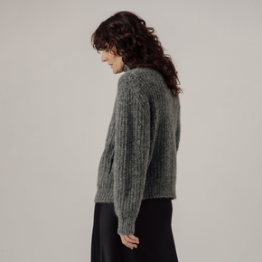 Woman wearing a gray rib knit jacket against a plain background