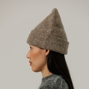 Person wearing a beige knit beanie against a plain background