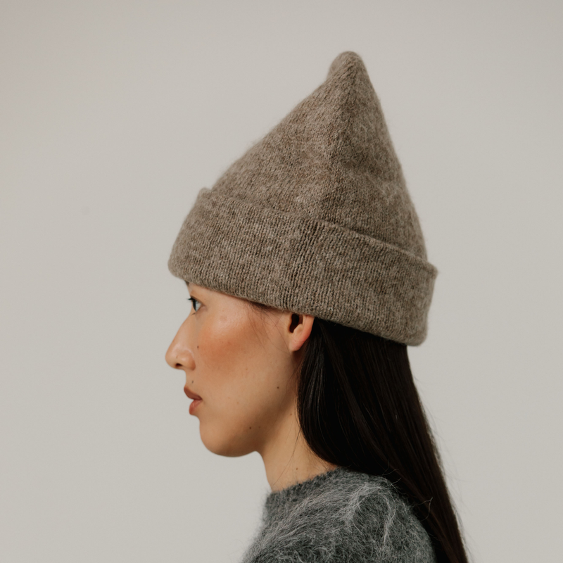Person wearing a beige knit beanie against a plain background