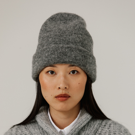 Person wearing a gray knit beanie against a plain background