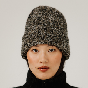 Person wearing a neutral multicolor rib knit beanie against a plain background
