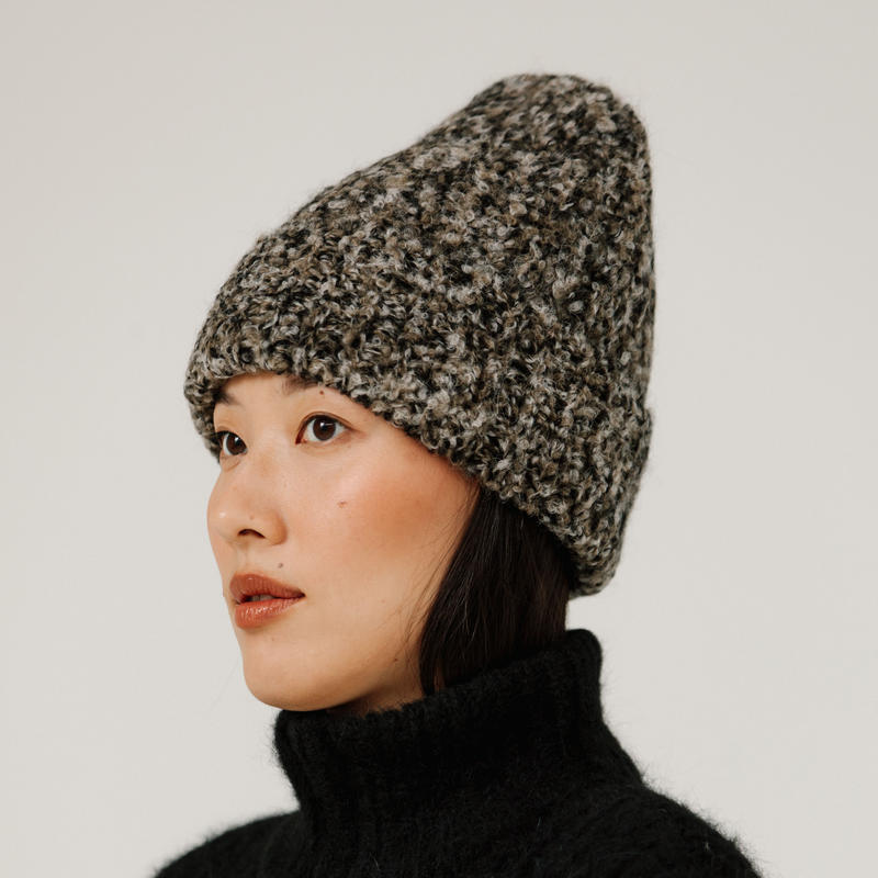 Person wearing a rib knit neutral multicolor beanie against a plain background