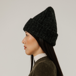 Person wearing a charcoal grey rib knit beanie against a plain background