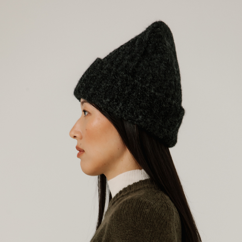 Person wearing a charcoal grey rib knit beanie against a plain background