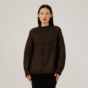 Woman wearing a brown sweater against a plain background