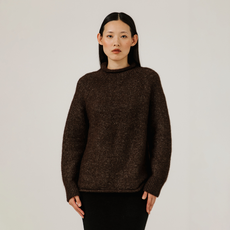 Woman wearing a brown sweater against a plain background