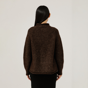 Person wearing a brown sweater against a plain background