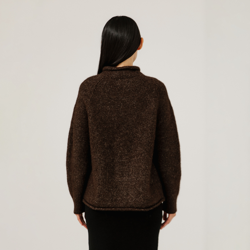 Person wearing a brown sweater against a plain background