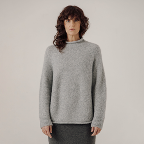 Person wearing a gray sweater against a plain background