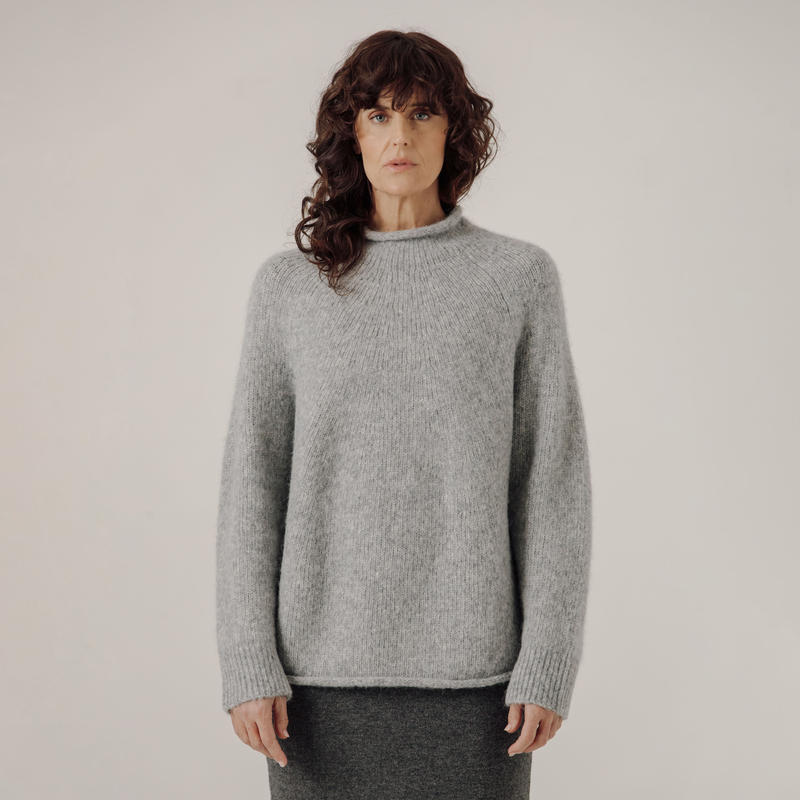 Person wearing a gray sweater against a plain background