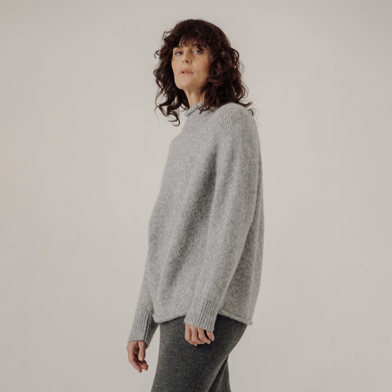 Woman wearing a gray sweater against a plain background