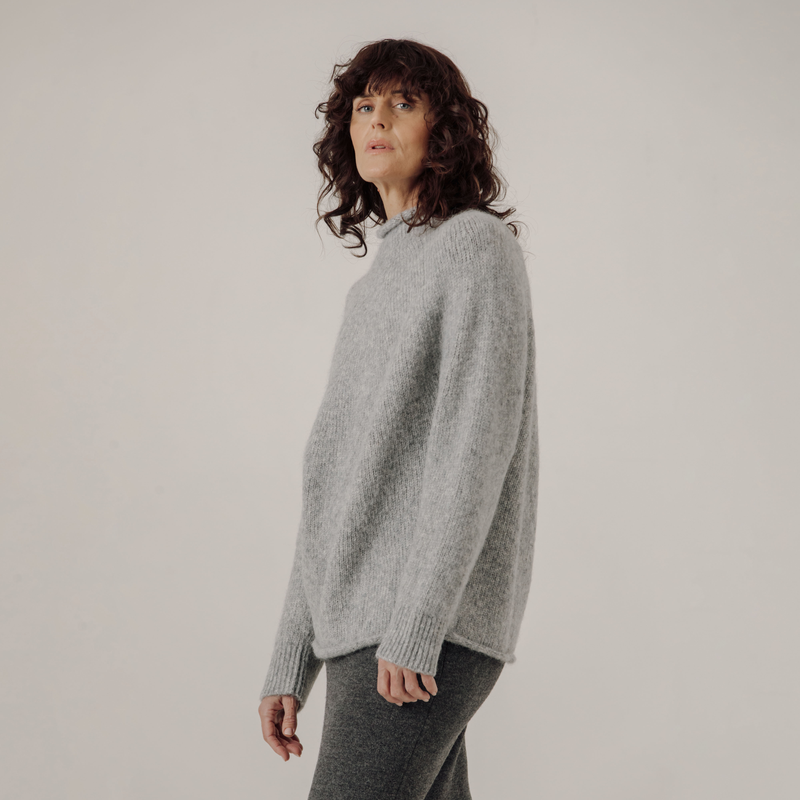 Woman wearing a gray sweater against a plain background