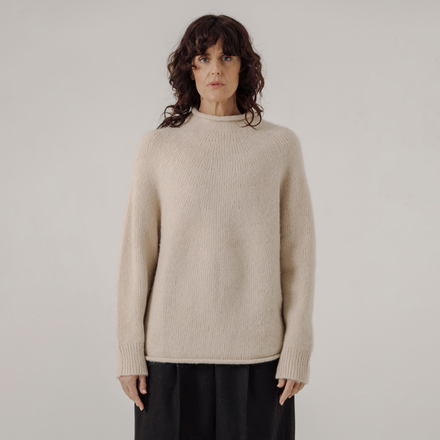 Woman wearing a white sweater against a plain background