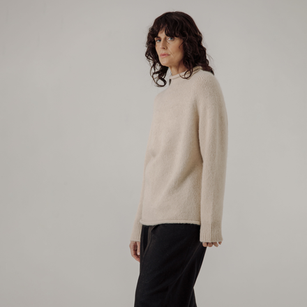 Woman wearing a white sweater against a plain background