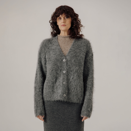 Woman wearing a gray cardigan against a plain background