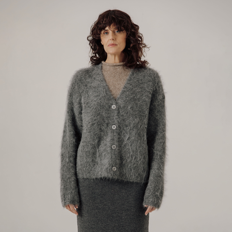 Woman wearing a gray cardigan against a plain background