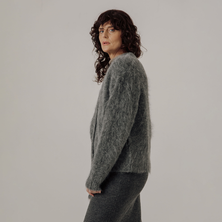 Woman wearing a gray cardigan against a plain background