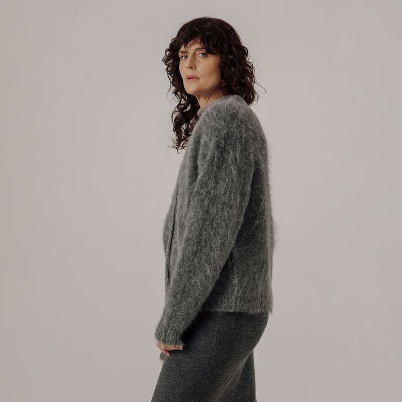 Woman wearing a gray cardigan against a plain background
