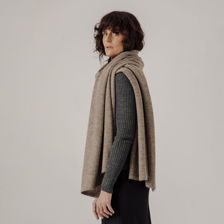 Woman wearing a beige scarf against a plain background