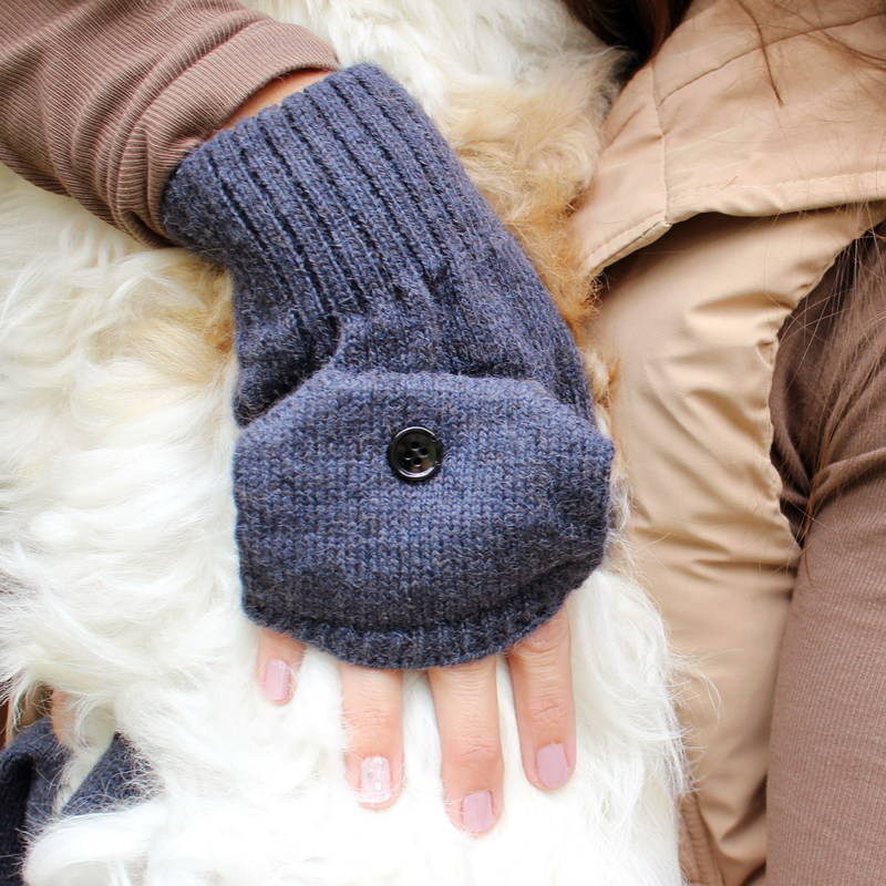 Blue knitted glitten with a button on a white fur surface
