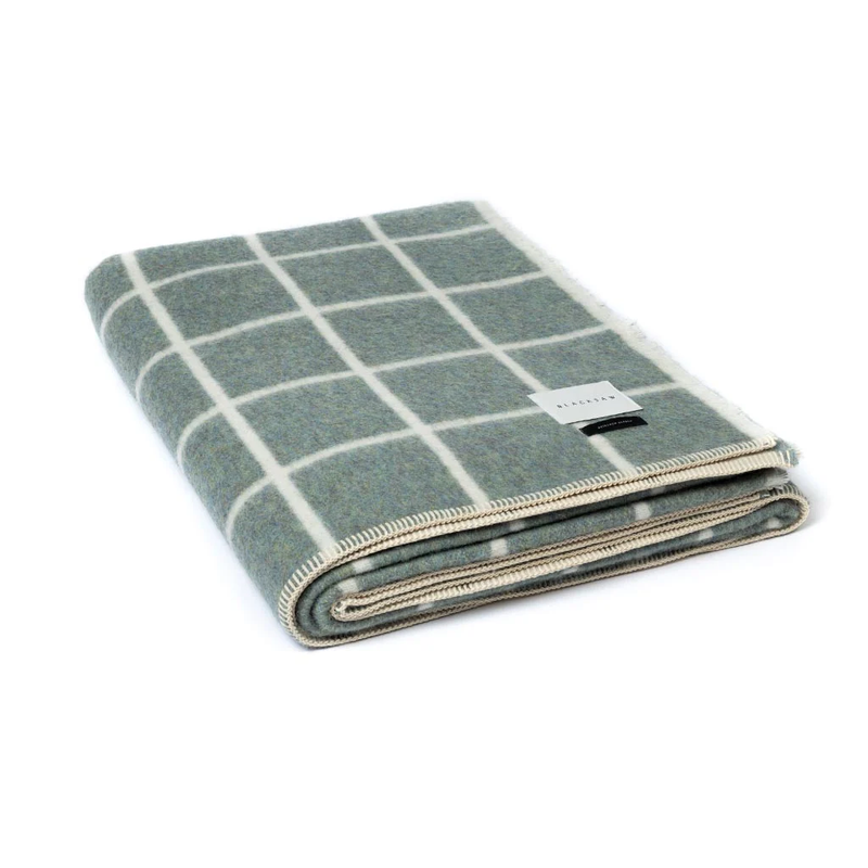 Folded blanket with green and beige checkered pattern on a white background