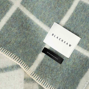 Plaid blanket with 'BLACKSAW' label on a checkered pattern