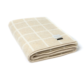 Folded beige blanket with white grid pattern on a white background