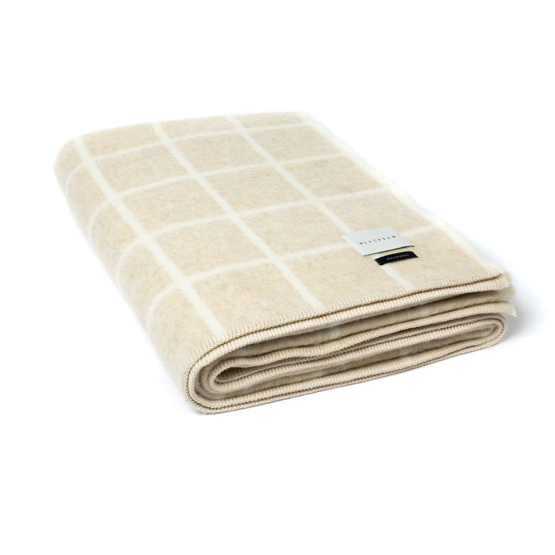 Folded beige blanket with white grid pattern on a white background