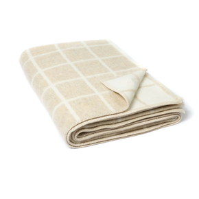 Folded beige blanket with a grid pattern on a white background