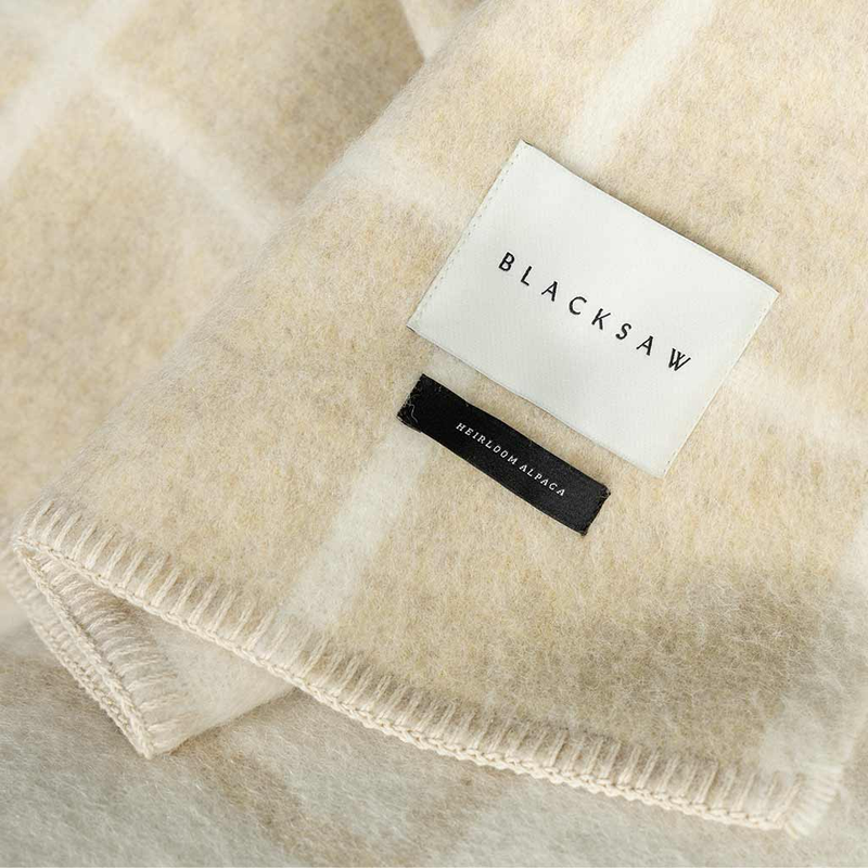 Beige blanket with 'BLACKSAW' label on a light background