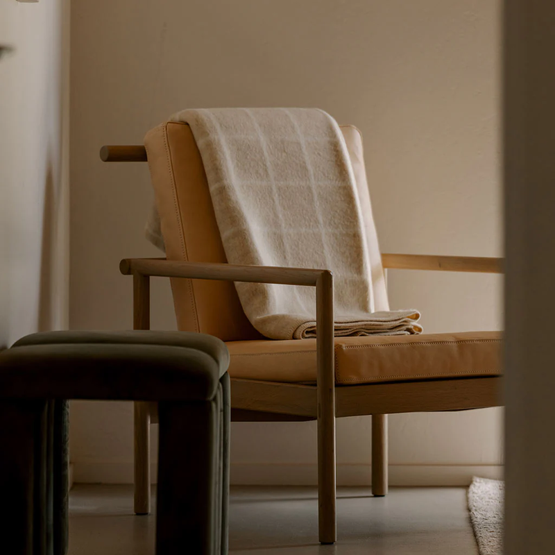 Brown chair with a beige blanket draped over it in a softly lit room.