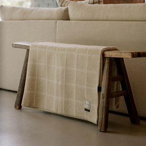 Beige checkered blanket draped over a wooden bench in a living room setting.