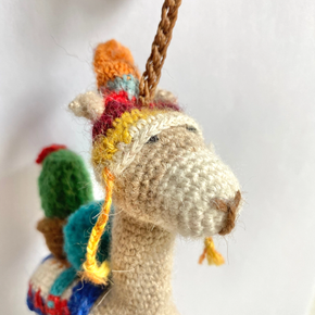 Knitted alpaca ornament with colorful blanket on a white background