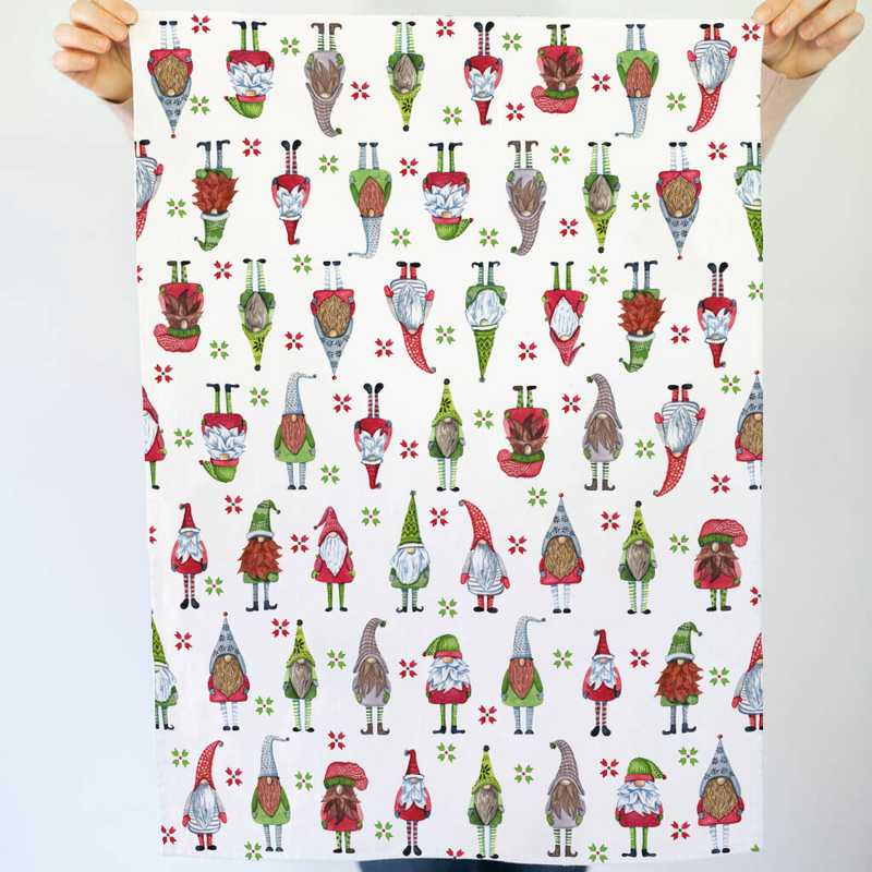 Tea towel with a colorful pattern of cartoon gnomes held by two hands.