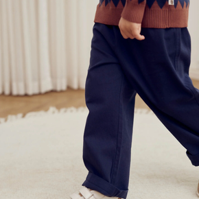 Navy blue pants worn by a child indoors on a light-colored carpet.