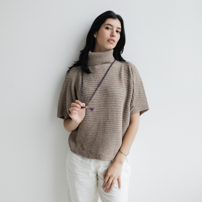 Woman wearing a beige turtleneck sweater against a plain background