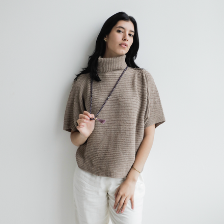 Woman wearing a beige turtleneck sweater against a plain background